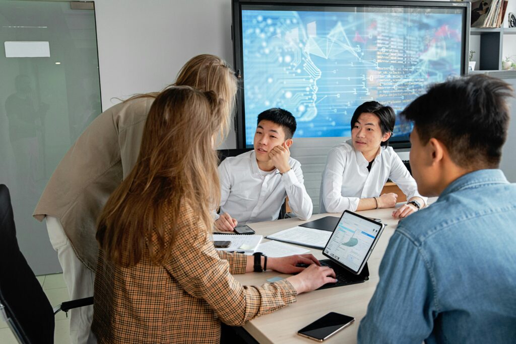 Three Signals Your Team Is Growing Too Fast Team of professionals collaborating in an office with digital interface on background screen.