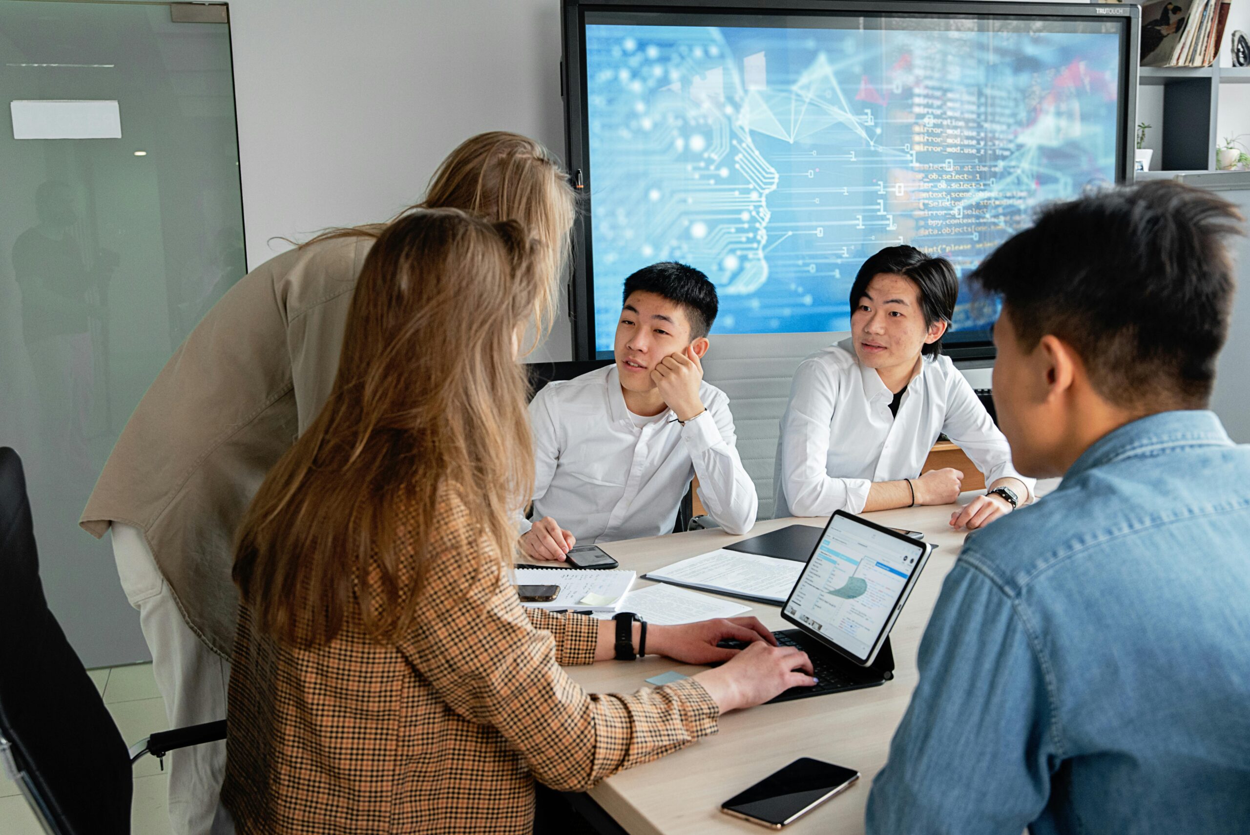 Blogs Team of professionals collaborating in an office with digital interface on background screen.