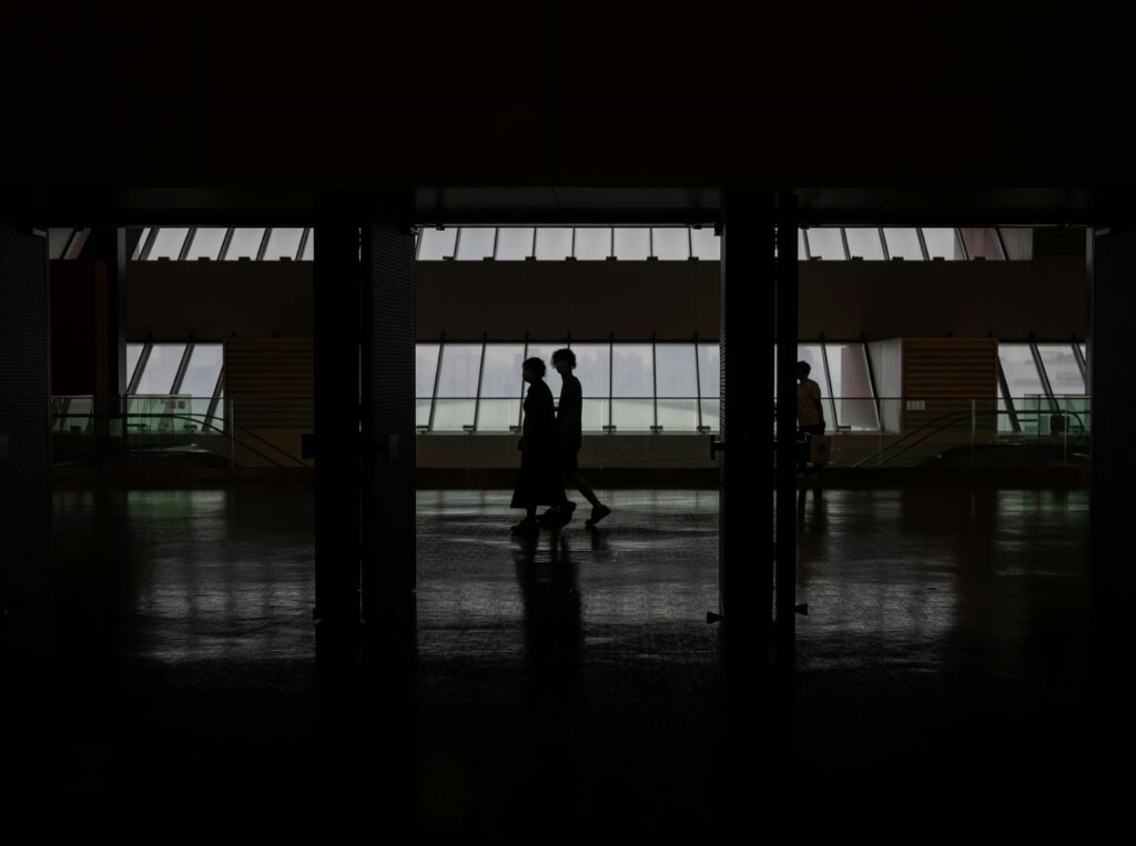 Quiet Problems That Appear When Teams Scale Silhouette of people walking through a modern hallway with large windows in Shanghai, China.